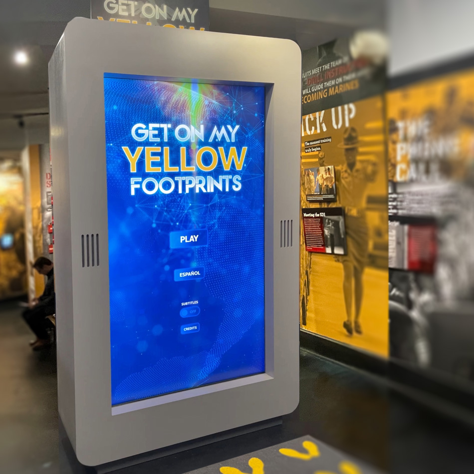 The 85-inch kiosk displaying the Get on My Yellow Footprints attractor screen
