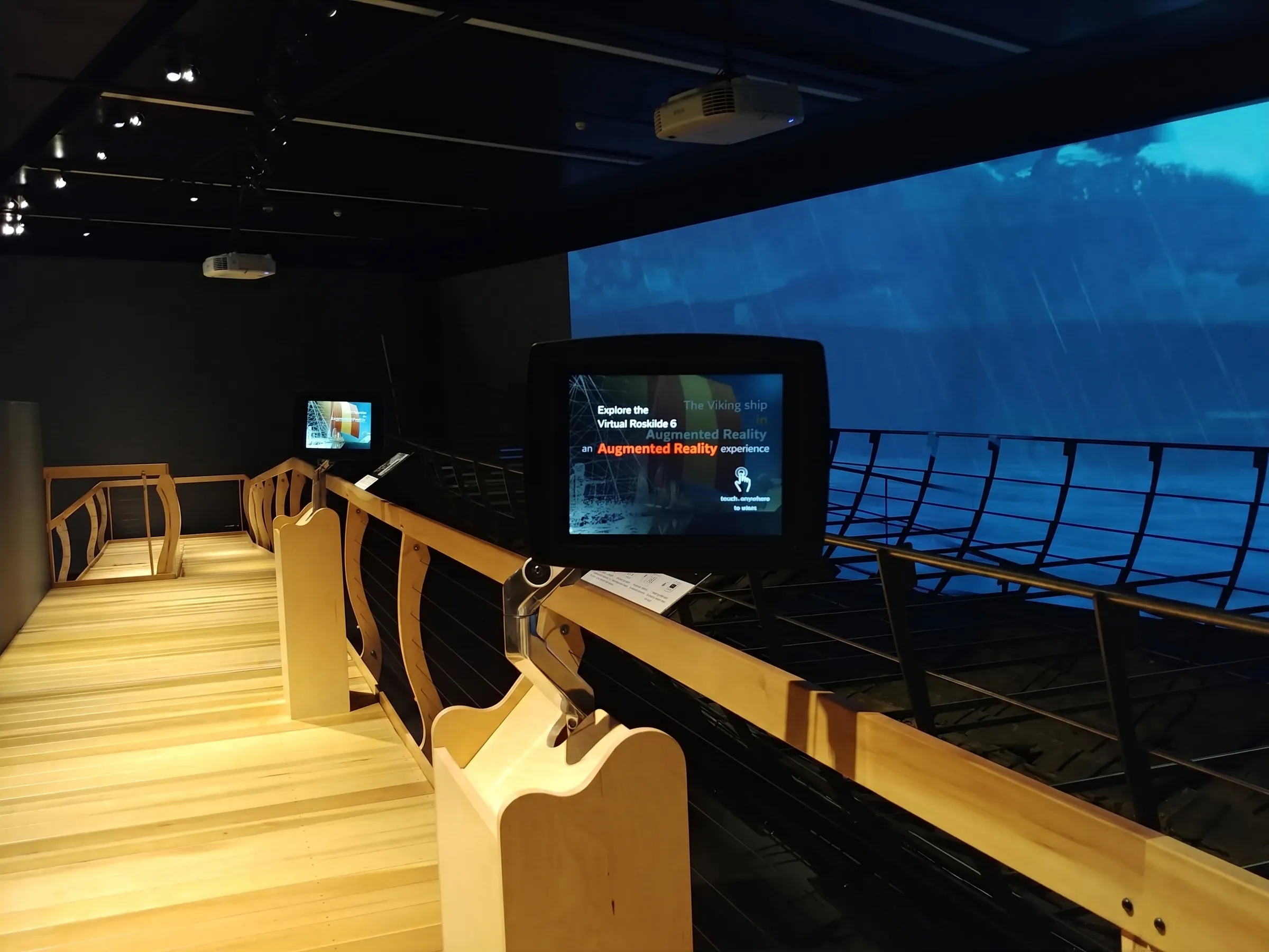 Visitor using a tablet to view the AR overlay of the Roskilde 6 reconstruction